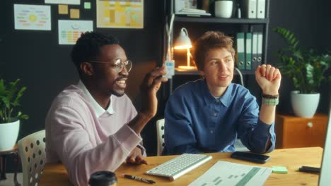 diverse coworkers discussing business plan on computer in office