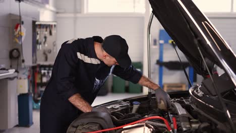 mechanic in a auto repair shop checking engine manually