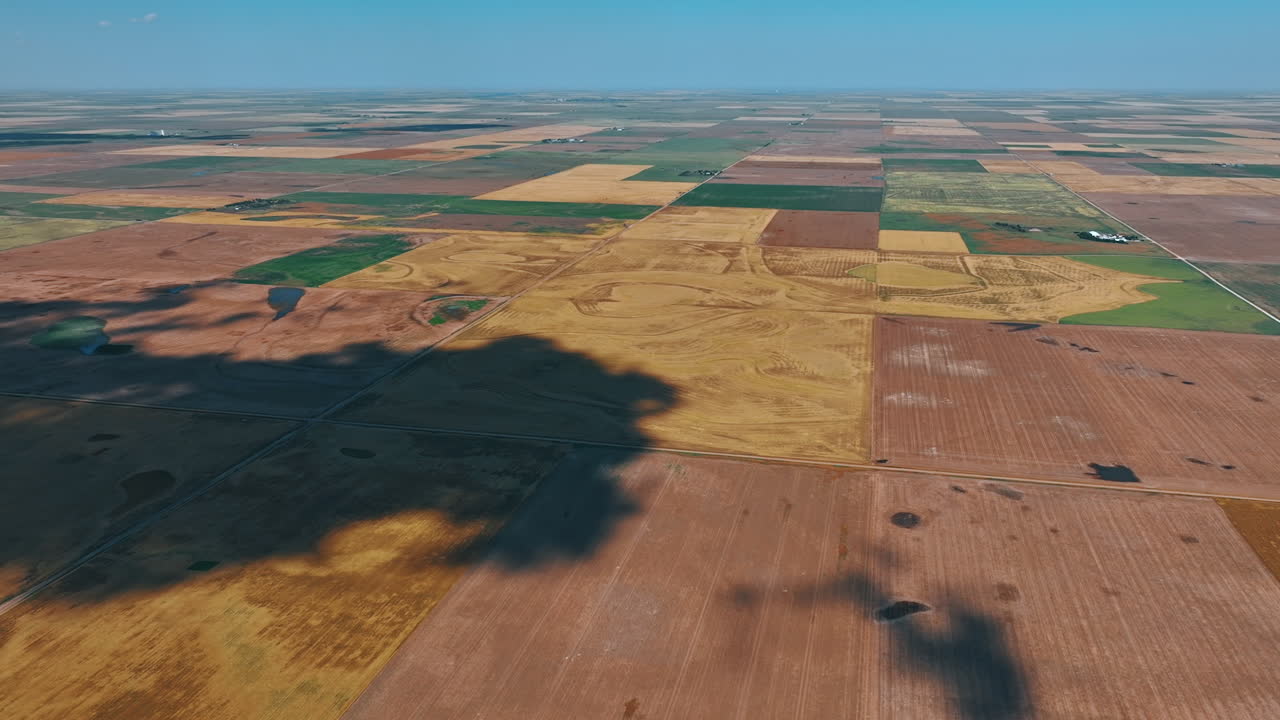 Shadow from a big cloudscape moves by the ground. Aerial view on the fields prepared for agricultural purposes.