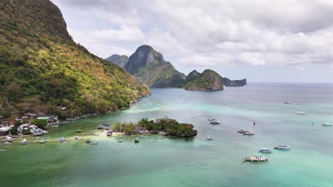 traditional boats float in bacuit bay, surrounded by the dramatic karst limestone formations, tropical foliage of el nido, a coastal paradise on palawan island facing the south china sea, static shot