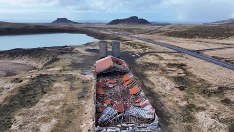 remote iceland farm, in various stages of decay, features a collapsed roof, scattered debris, and a serene lake in the distance, demonstrating nature's reclaiming power