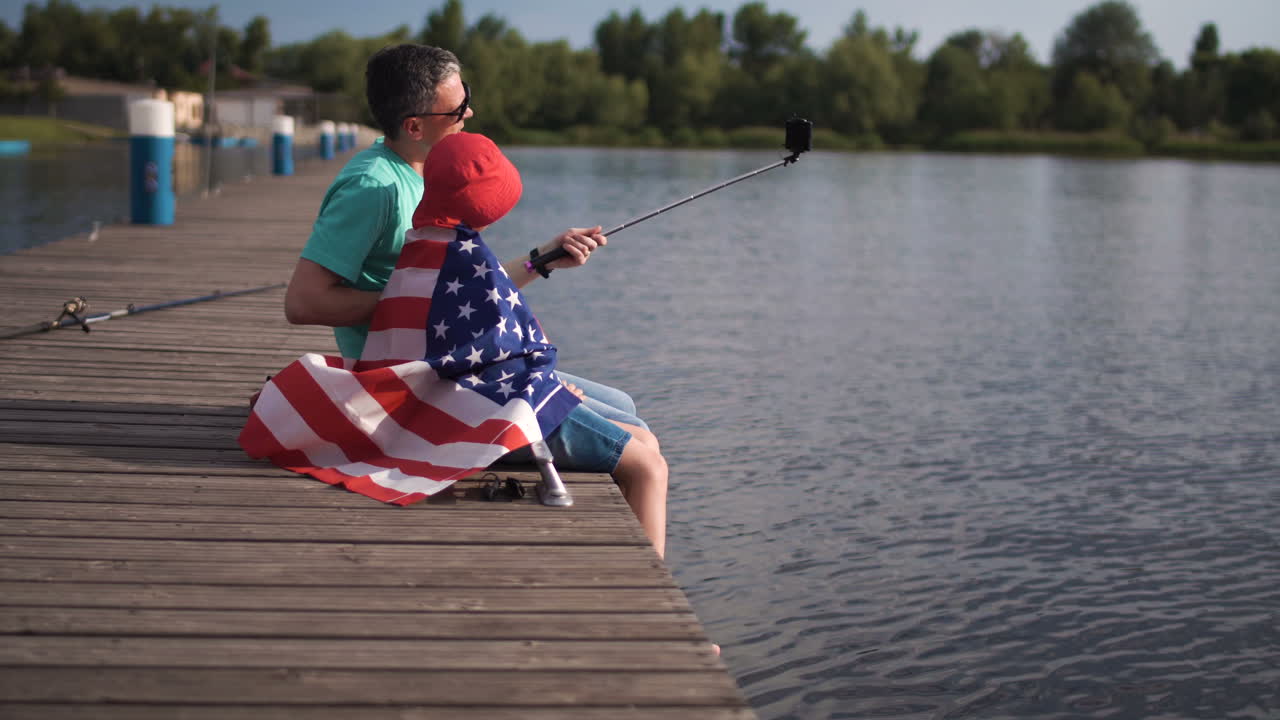 Father and Son Taking a Selfie on a Lake Pier