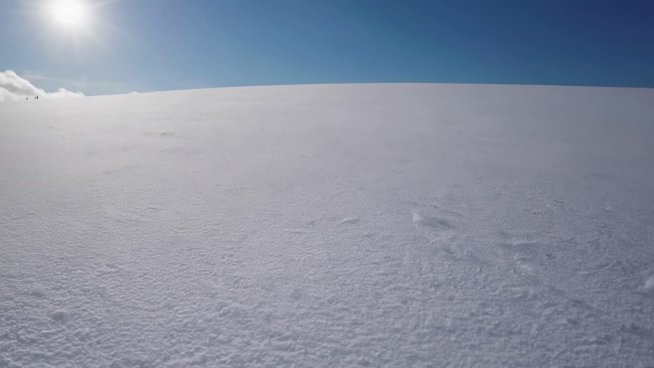Wide-angle video shot of a snow-covered landscape under a clear blue sky, capturing the serene