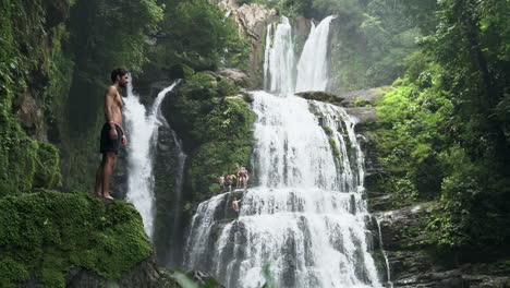 man stands in front of nauyaca waterfalls costa rica with leaves in foreground