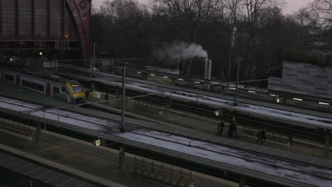 wide shot showing people arriving train station during cold freezing day early in morning