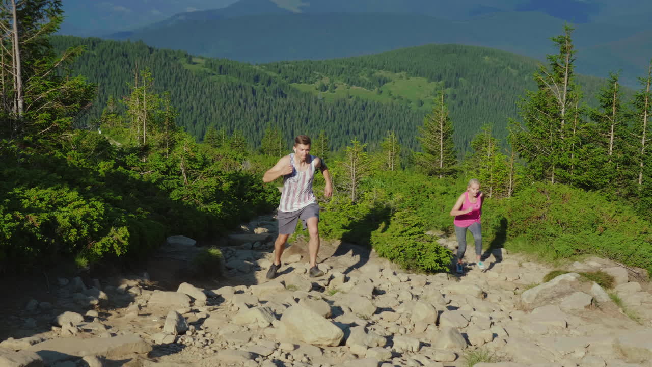 carrera extrema una mujer con un entrenador personal corre por un camino empinado de montaña en las montañas fro