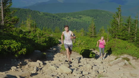 Extrema-Corriendo-Una-Mujer-Con-Un-Entrenador-Personal-Corre-Por-Un-Sendero-De-Montaña-Empinada-En-Las-Montañas-Para