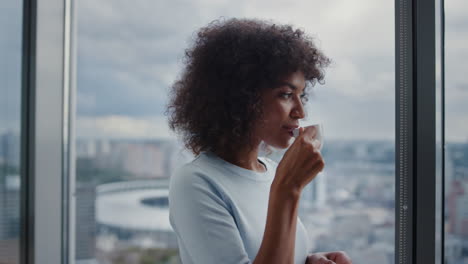 Mixed-race-businesswoman-drinking-coffee-on-city-view.-Executive-taking-break