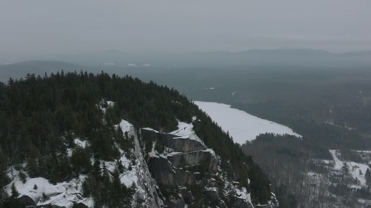 volar lejos en las montañas rocosas con un hombre de pie en la parte superior durante el invierno en quebec, canadá