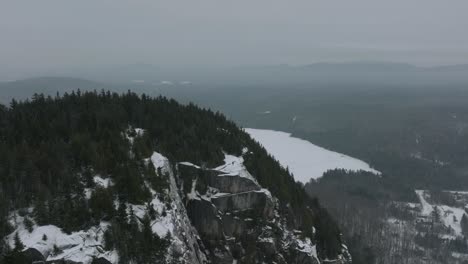 Fly-Away-At-Rocky-Mountains-With-A-Man-Standing-On-Top-During-Winter-In-Quebec,-Canada