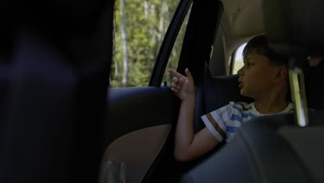 Video-De-Un-Niño-Señalando-Algo-A-Través-De-La-Ventanilla-De-Un-Auto.