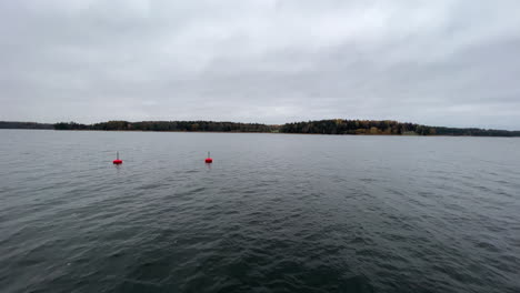 Wide-view-of-two-floating-red-buoys-in-the-Stockholm-archipelago,-cloudy