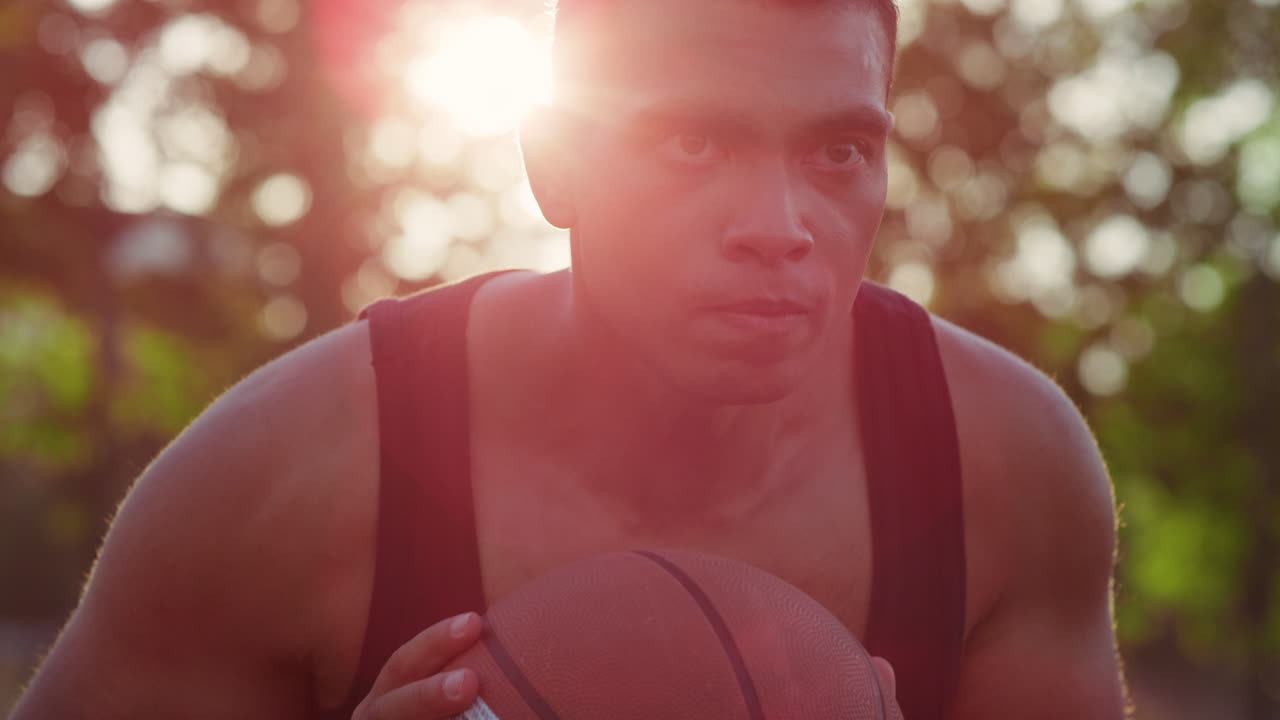 un deportista serio practicando baloncesto callejero al aire libre.