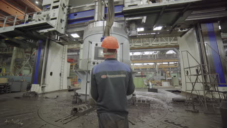 metal part being processed on a large industrial lathe by a technician