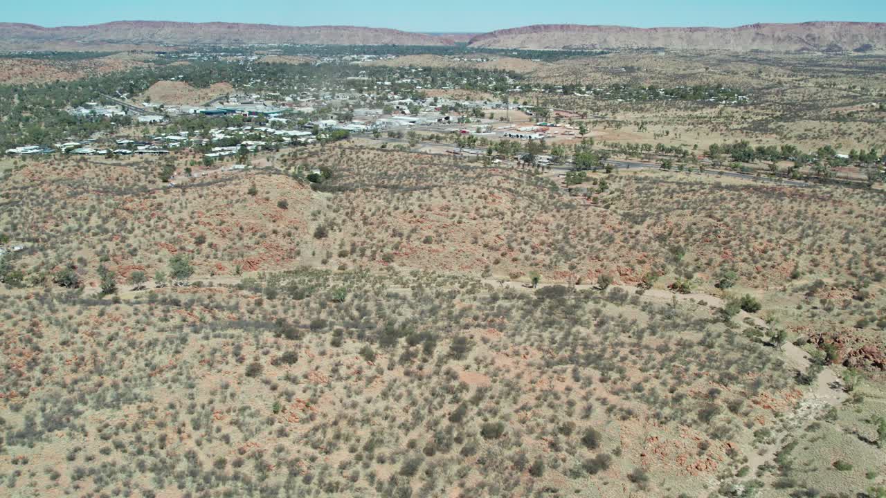 Aerial view of the landscape with the town of Alice Springs, Mparntwe, in the distance. Northern Territory, Australia. August 2022.
