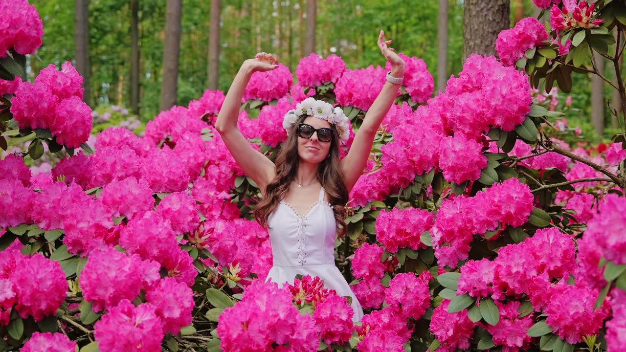 Elegancia primaveral mientras una mujer se mueve como en un club entre vibrantes flores de rododendro.