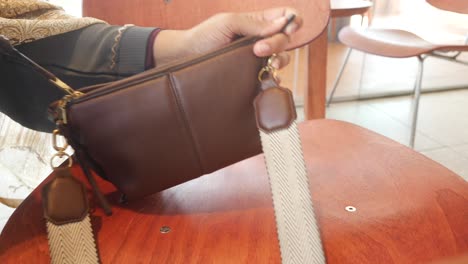 woman opening a brown leather shoulder bag