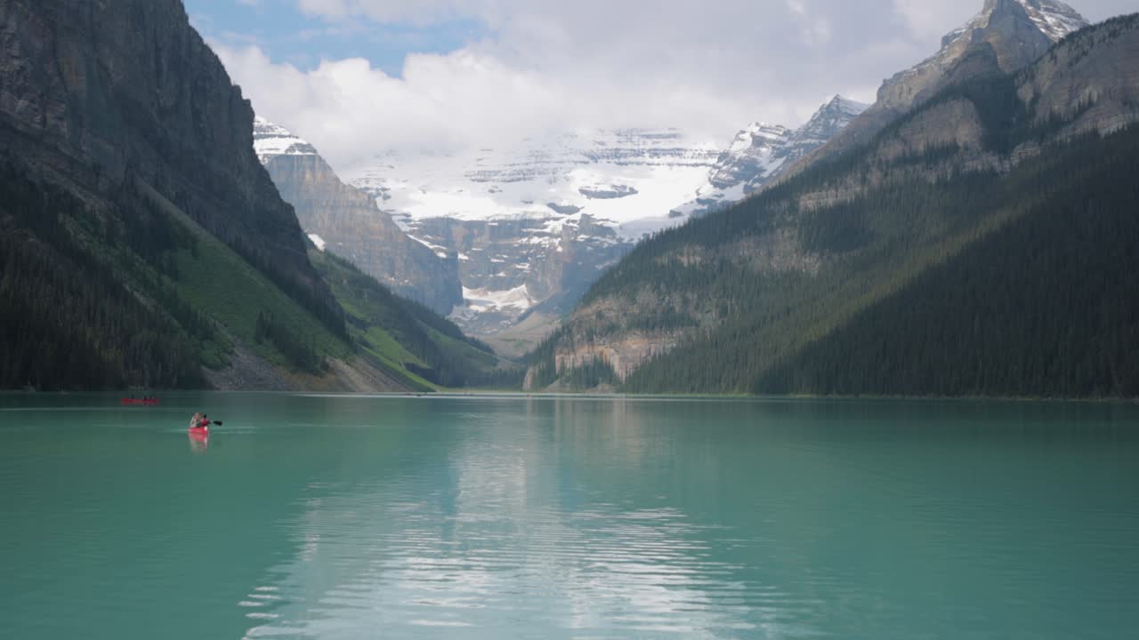 Beautiful Lake Louise with tourists canoeing and the mountains in the background in Banff National Park.