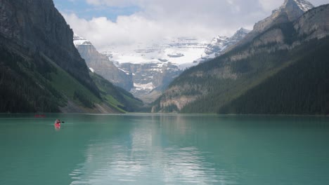 beautiful lake louise with tourists canoeing and the mountains in the background in banff national park.