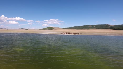 Vergrößern-Sie-Den-Blick-Vom-See-In-Der-Mongolei-Auf-Eine-Pferdeherde,-Die-Am-Wasser-Entlang-Läuft.-Antenne