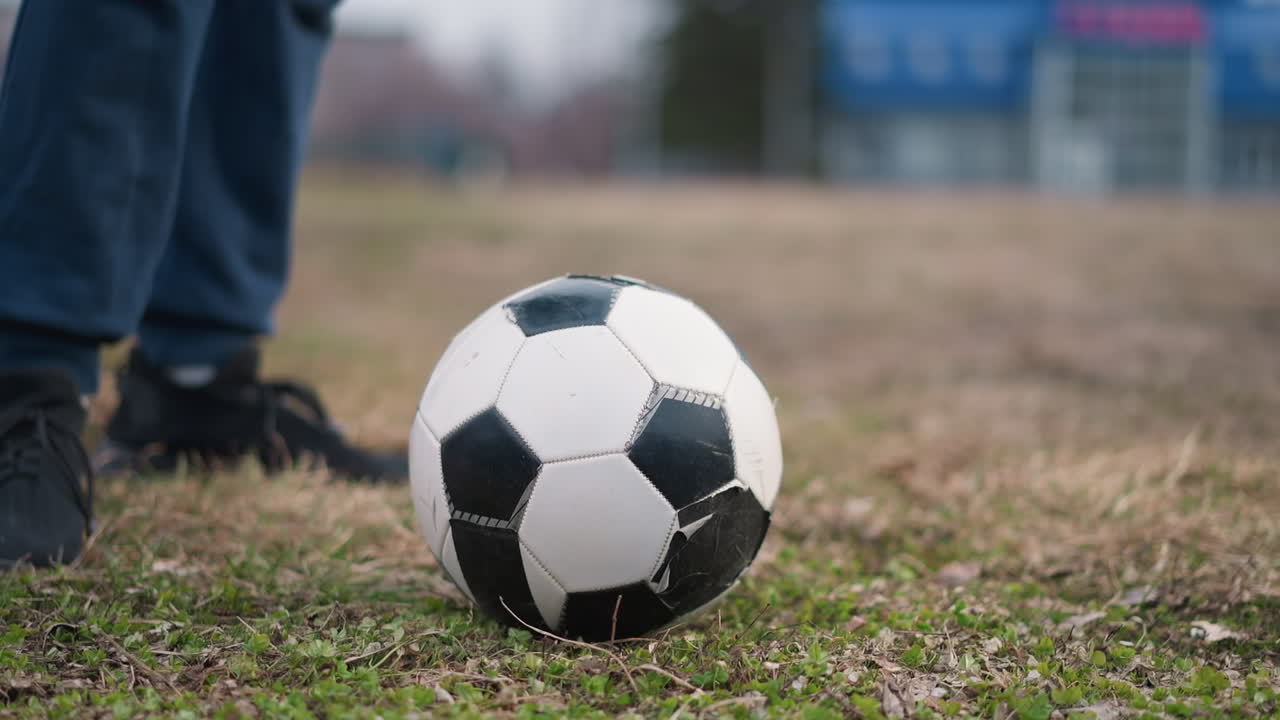 Close-up of someone's leg on a soccer ball on a grassy field with a blurred background