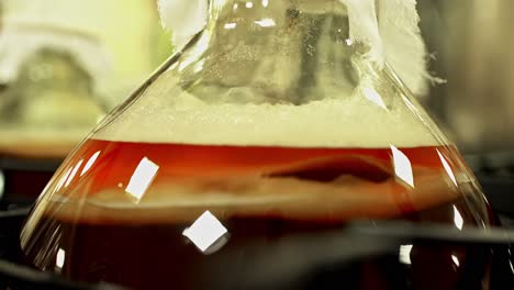 amber liquid in a large glass vase reflects bright square lights, creating visual glow