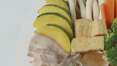 cerca de un cuenco de sukiyaki o shabu girando alrededor de la mesa blanca