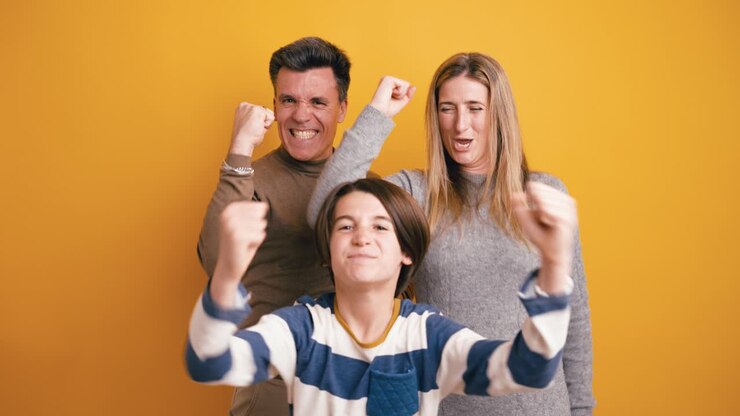 Famiglia entusiasta che esulta e celebra il successo su sfondo giallo