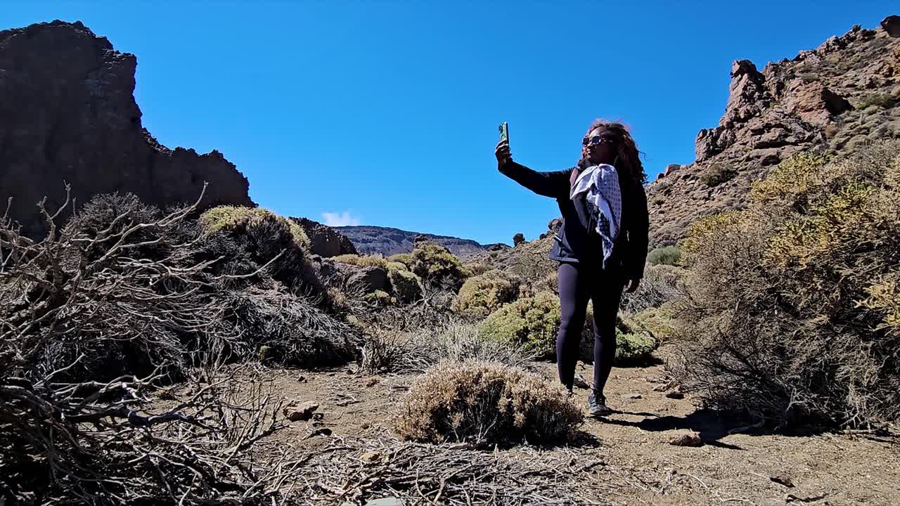 Young woman taking a selfie in a rocky desert landscape in Roques de Garcia, Spain