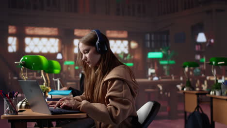 vertical video young girl listening to educational documentary on laptop and takes notes