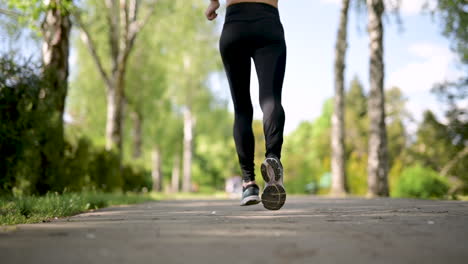 back view of a sportswoman running at the park in a sunny day