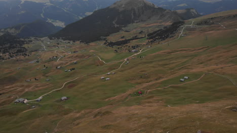 Aerial-shot-from-drone-revealing-young-male-model-standing-on-the-edge-of-a-rock-overlooking-the-Dolomite-valleys-from-above,-Italy