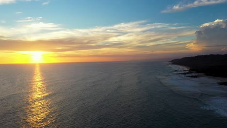 antena de hermosa puesta de sol reflejándose en el agua con olas y surfistas en el océano pacífico en tamarindo, costa rica