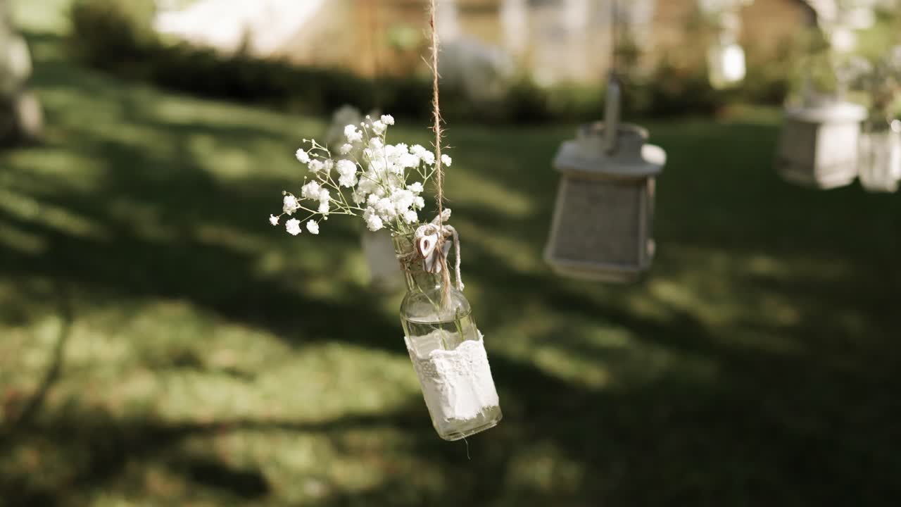 rustic glass jar with lace and baby's breath flowers hanging in outdoor garden sunlight