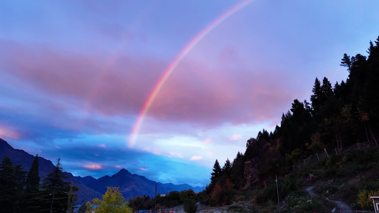 magnífico doble arco iris en el cielo al anochecer sobre el bosque y las montañas junto a walter peak en queenstown