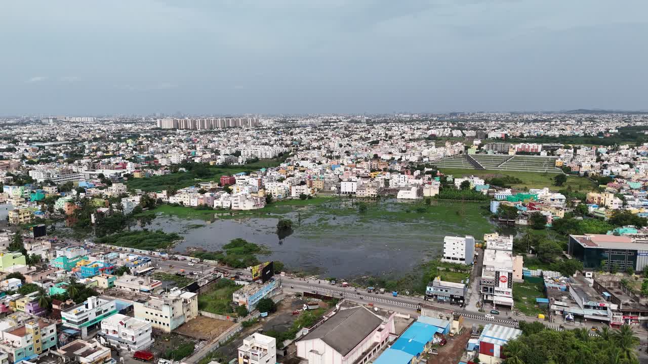 Wide aerial of a large, developing city's infrastructure. A huge elevated road cuts through dense housing, showing the mix of older homes and new, tall buildings in distance