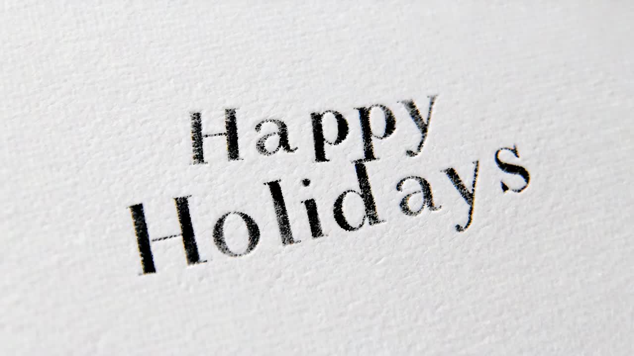 Zooming lens revealing Happy Holidays serif text on toothy paper, showing ink impression for detail