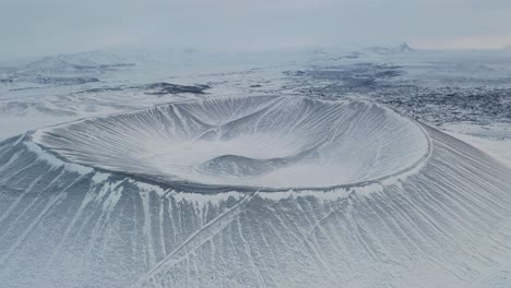 aerial flyover majestic hverfjall tuff ring volcano covered with snow and ice in iceland