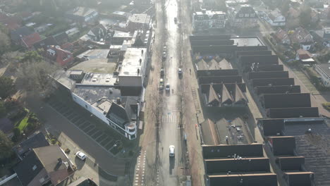 Aerial-of-car-driving-over-long-road-through-suburban-shopping-district