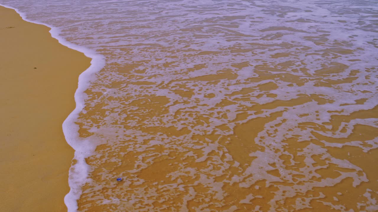 바다 해변의 텍스트 해변과 자연 개념의 슬로우 모션 파동으로 모래에 파도가 튀는