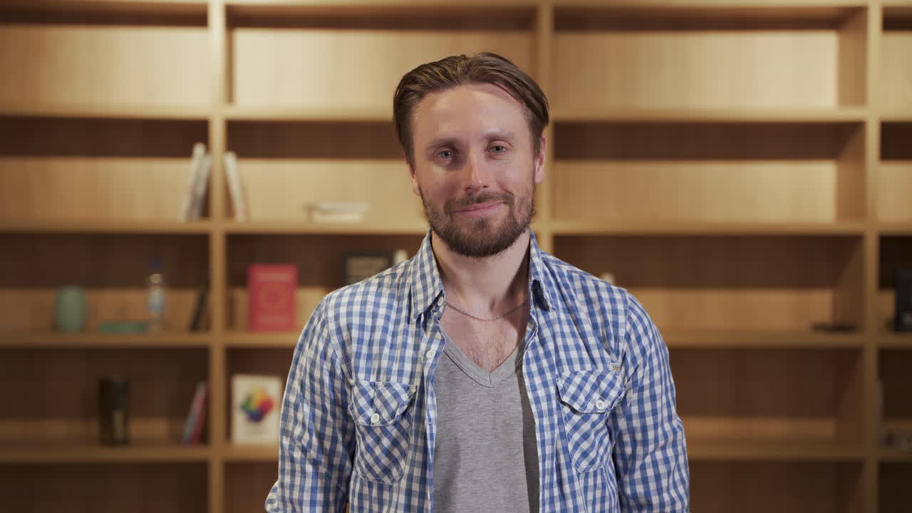 A handsome bearded man looks smiling directly into the camera