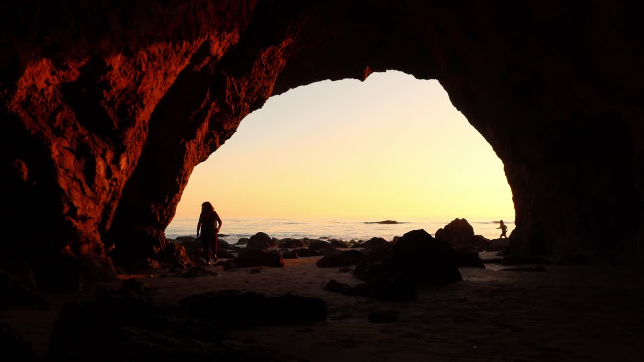 guy walking into a Sea cave at El matador beach Malibu California