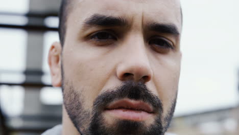 close-up view of handsome bearded sportsman looking with serious expression at the camera on a cloudy morning