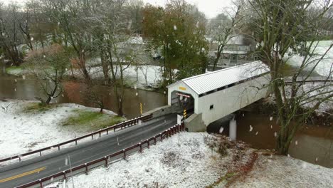 snow flurries at white covered bridge in rural usa