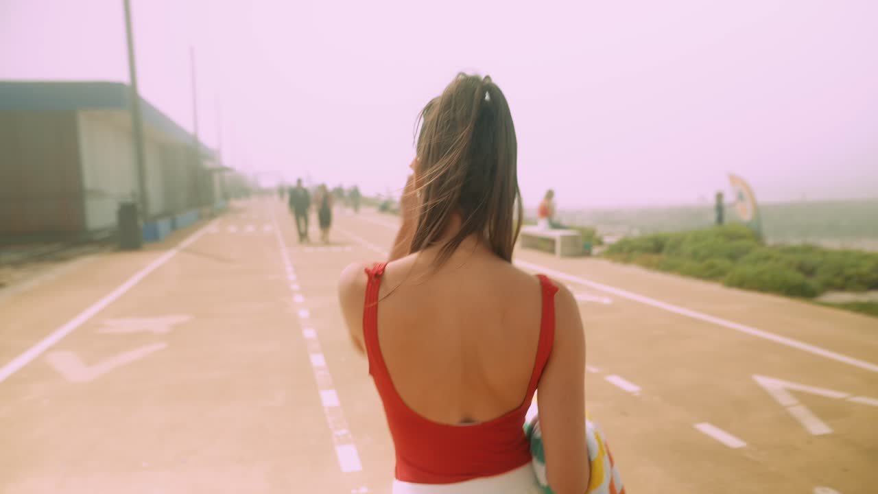 Giovane donna in costume da bagno rosso che cammina sul lungomare