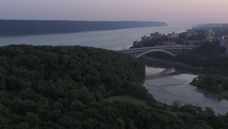 Wunderschöner-Blue-Hour-Luftflug-über-Den-Inwood-Hill-Park-In-Richtung-Der-Henry-Hudson-Bridge-An-Der-Spitze-Von-Manhattan,-New-York-City,-Ausblicke-Und-Spuyten-Duyvil,-Die-Palisaden-Von-New-Jersey-In-Der-Ferne