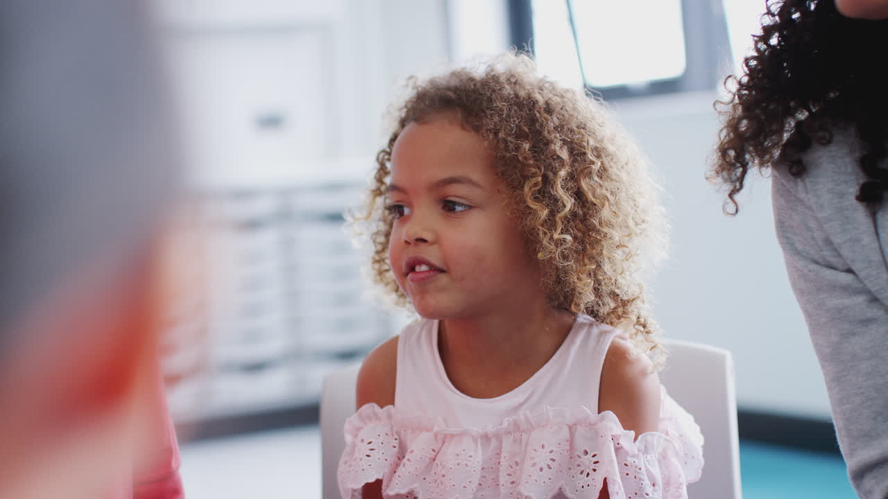 niña escolar de raza mixta en el aula con sus compañeros de clase y el maestro, de cerca, enfoque selectivo
