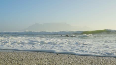 Olas-En-La-Playa-De-Blouberg-Con-Vistas-A-La-Montaña-De-La-Mesa-En-El-Horizonte