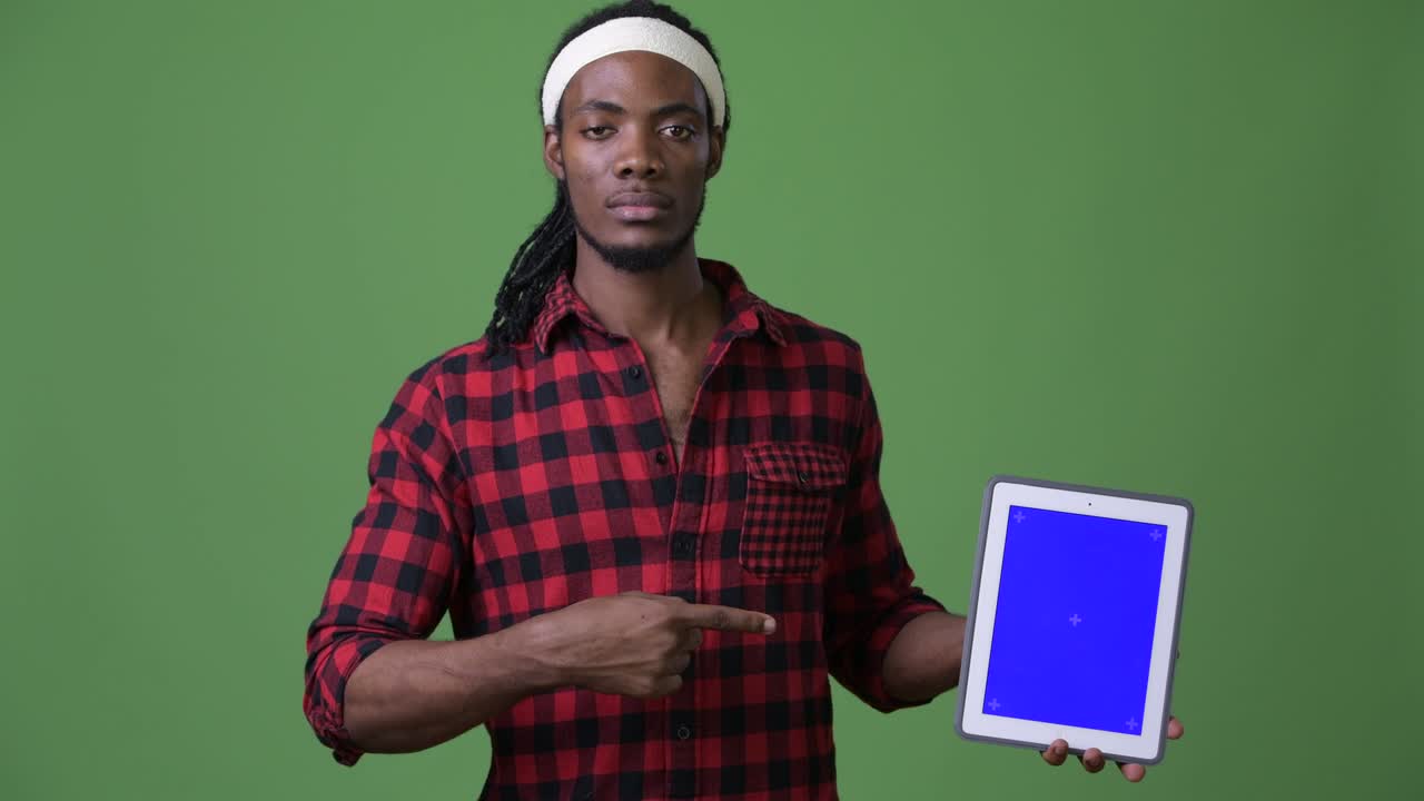 Young handsome African man with dreadlocks against green background