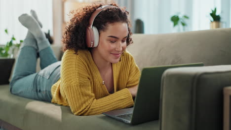 mujer relajándose en el sofá con computadora portátil y auriculares